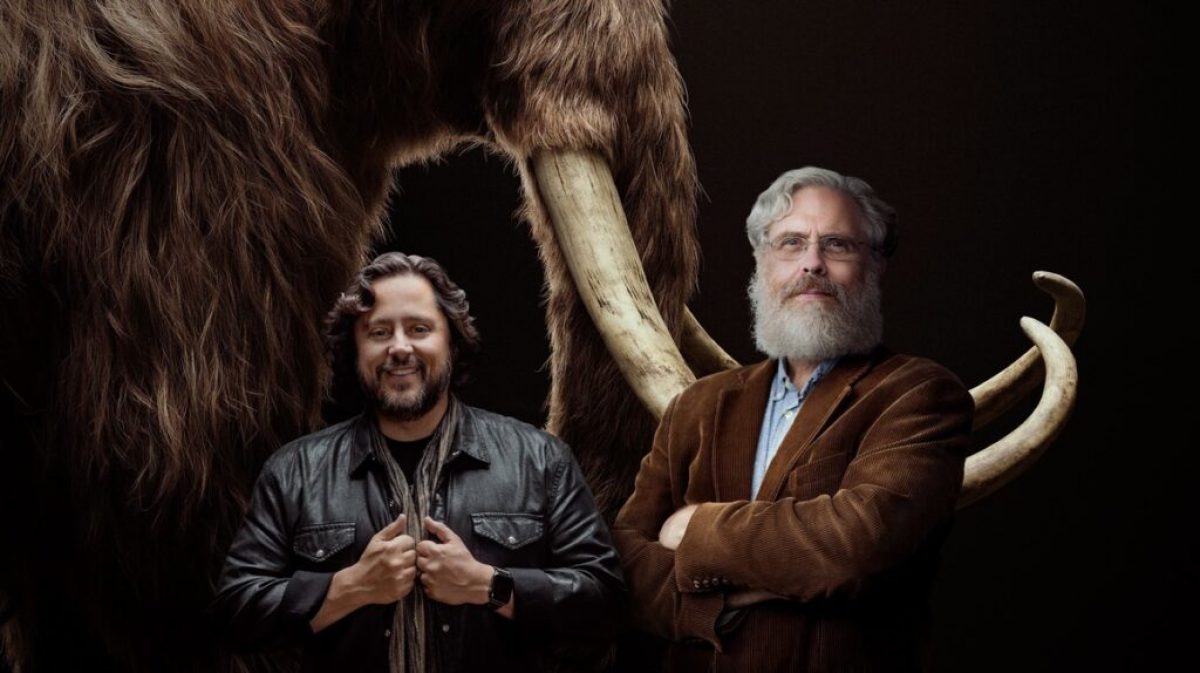 Fotografía cedida por la empresa Colossal donde aparecen sus cofundadores, los empresarios y científicos Ben Lamm (i) y George Church (d), mientras posan frente a la imagen de un mamut. - Foto: EFE