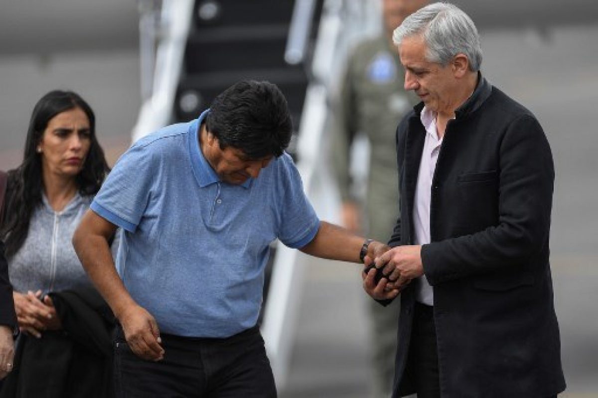 Álvaro García Linera, que renunció a la vicepresidencia de Bolivia, ayuda a Evo Morales luego de su aterrizaje en México. / AFP.