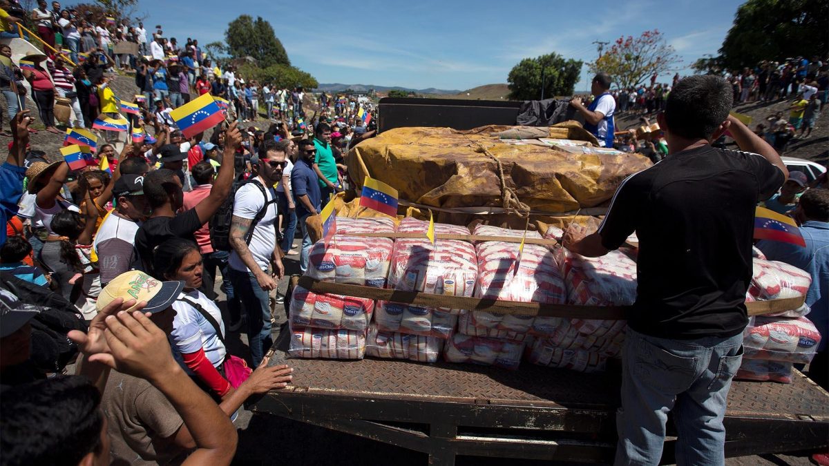 Personas celebran este sábado la llegada de la primera de las dos grandes camionetas cargadas con parte de la ayuda humanitaria de Brasil para Venezuela a la localidad Pacaraima, en el límite fronterizo entre ambos países (EFE).