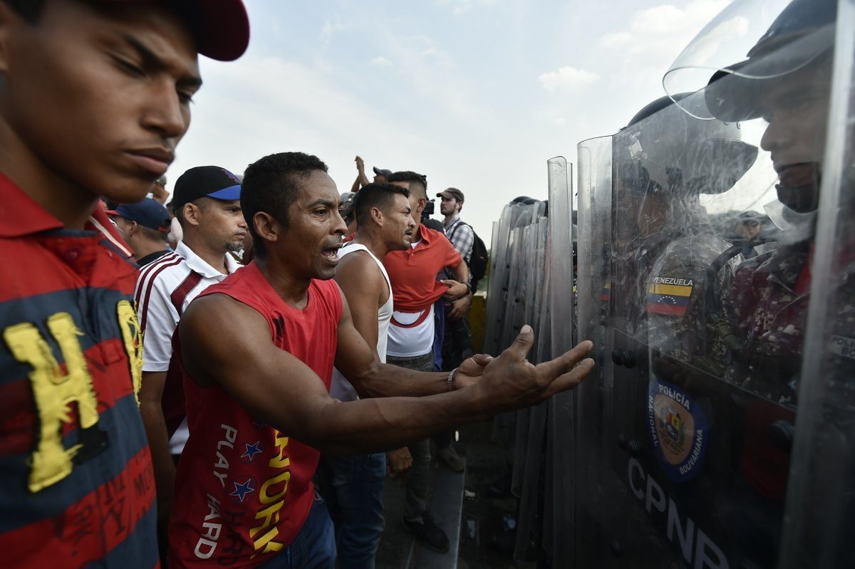 Los venezolanos se enfrentan a los policías nacionales y les piden que dejen la ayuda humanitaria en el puente Simón Bolívar (AFP).