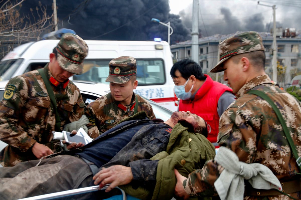 Agentes paramilitares y un personal médico transfieren a un hombre herido por la explosión detrás de ellos en Yancheng, en la provincia de Jiangsu, este de China.